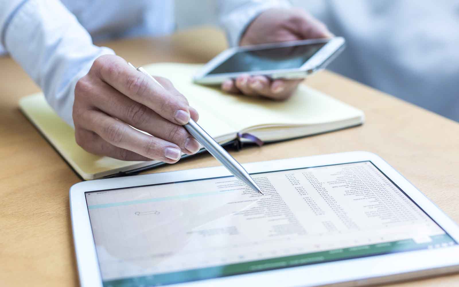 Person pointing to account data on a tablet while holding another tablet