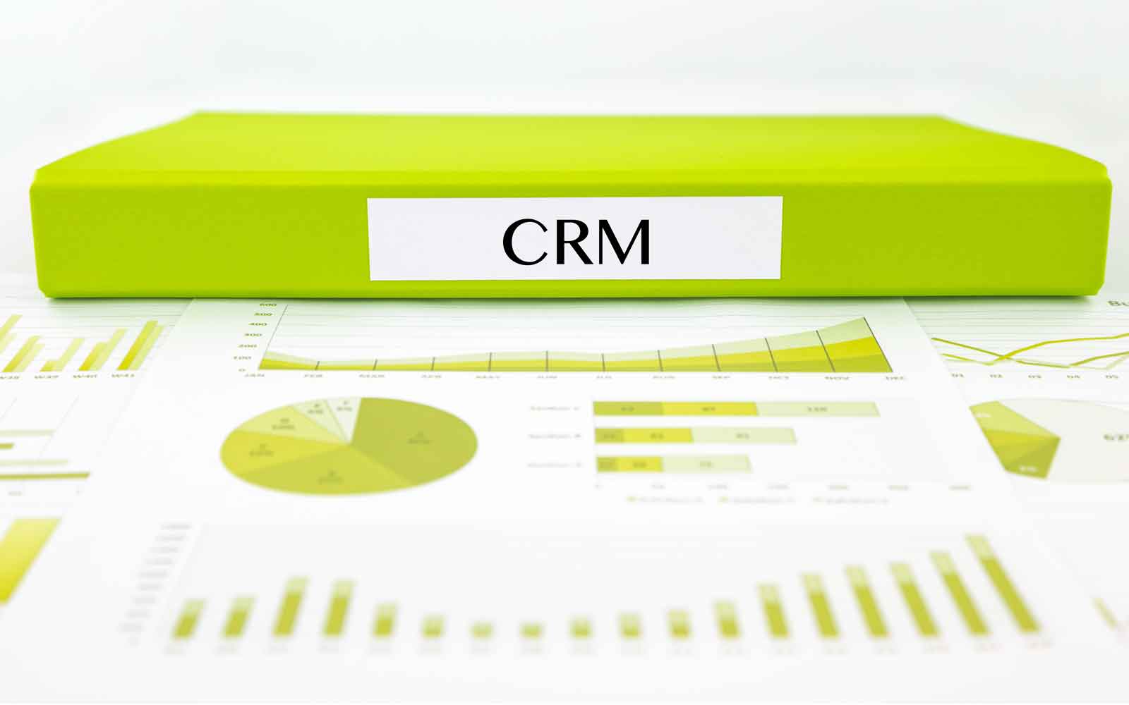 Green folder labelled CRM resting on printed charts and reports